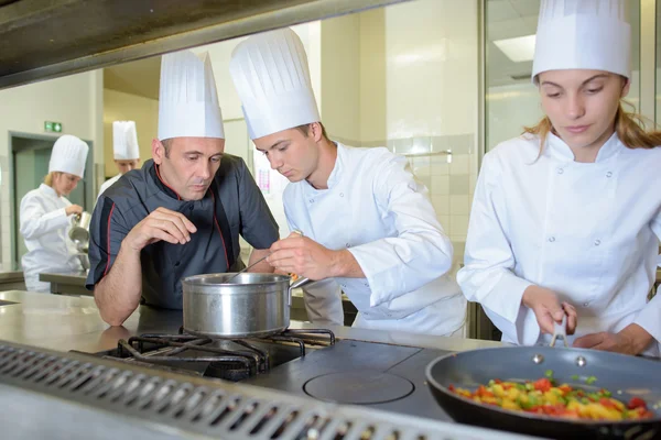 Chef chequeando el trabajo de los cocineros en prácticas —  Fotos de Stock