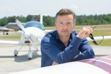 Man leaning on aircraft holding sunglasses clipart
