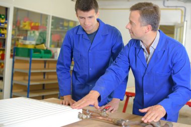 Instructor and apprentice looking at radiator clipart