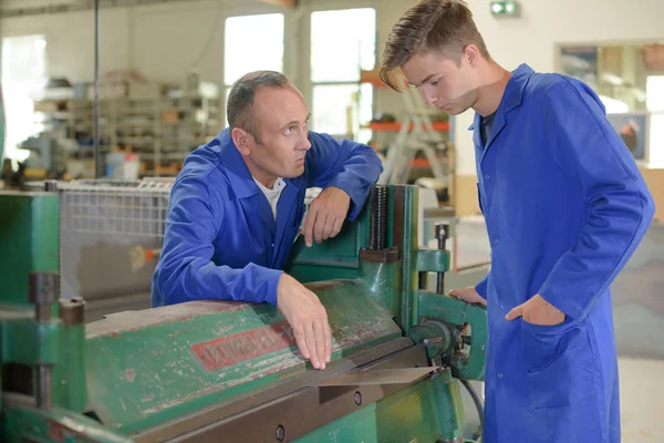 Man en de leerling door industriële machine — Stockfoto