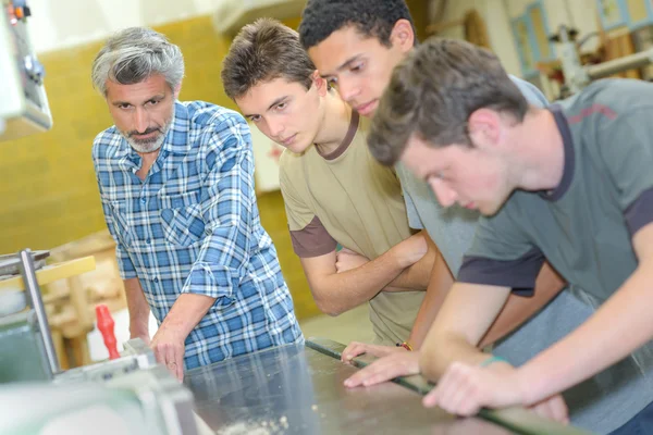 Três aprendizes do sexo masculino assistindo professor — Fotografia de Stock