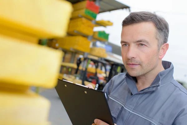 Workman tittar närmare på stacken av trä — Stockfoto