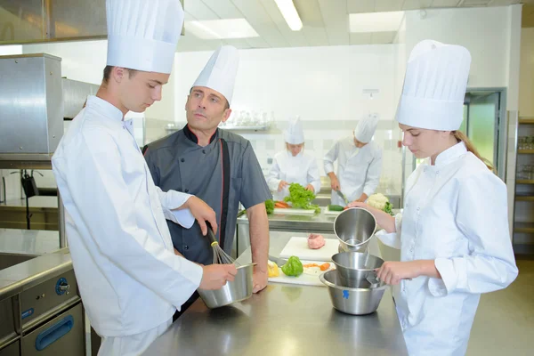 Estagiário cozinha sob a supervisão de um chef — Fotografia de Stock