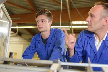Worker showing a machine to his apprentice clipart