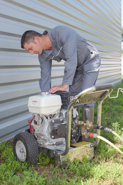 Man leaning over generator — Stock Photo, Image