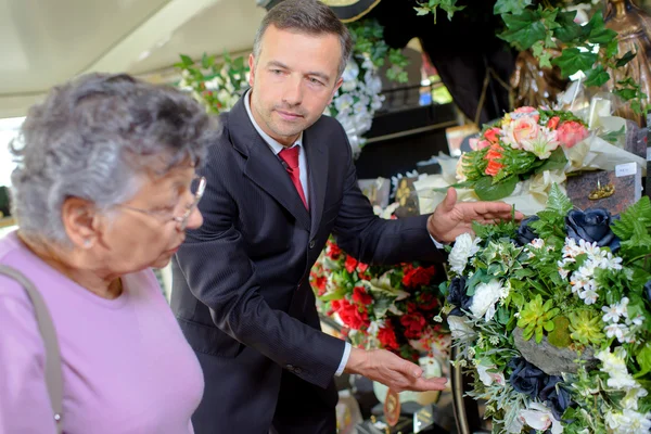 Pohřebník pomáhá žena si vybrat květiny — Stock fotografie