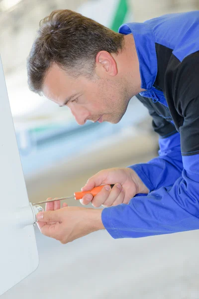 Handwerker mit Schraubenzieher am Heizkessel — Stockfoto