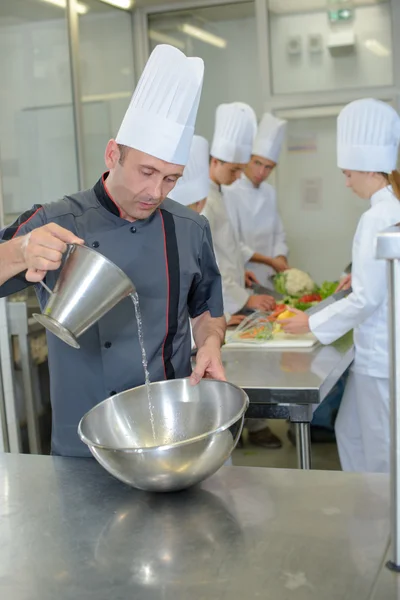 Chef derramando em tigela de aço inoxidável — Fotografia de Stock