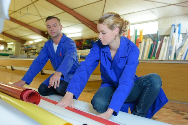 Mannen och kvinnan tittar på rullar av material — Stockfoto