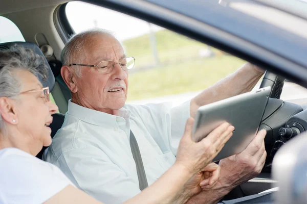 Älteres Ehepaar mit Tablet im Auto — Stockfoto