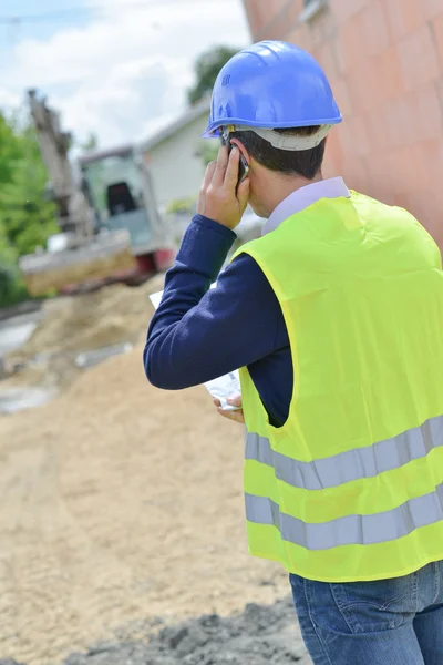 Hombre en el teléfono, mirando el sitio de construcción — Foto de Stock