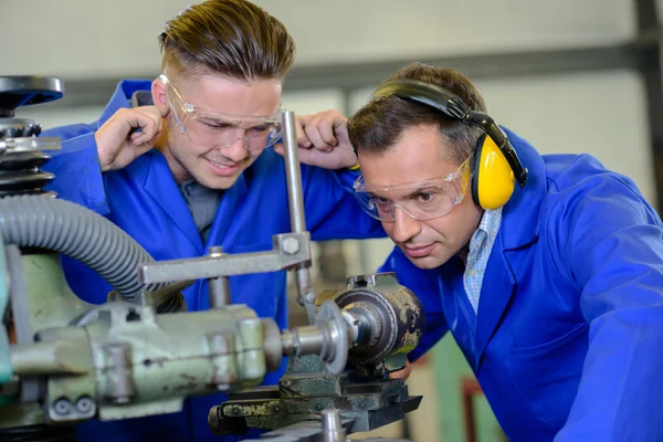 Ingeniero usando máquina aprendiz con los dedos en las orejas — Foto de Stock