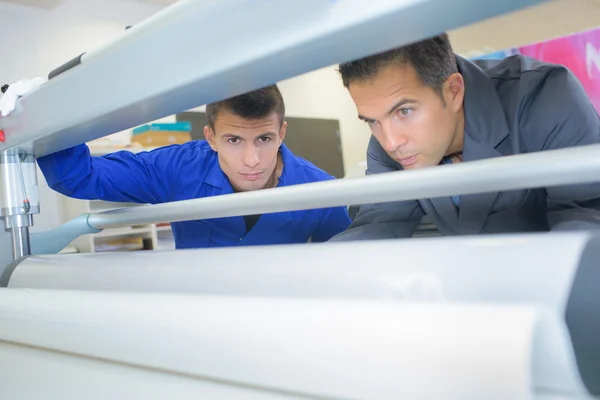 Dos hombres trabajando en la máquina de impresión industrial —  Fotos de Stock