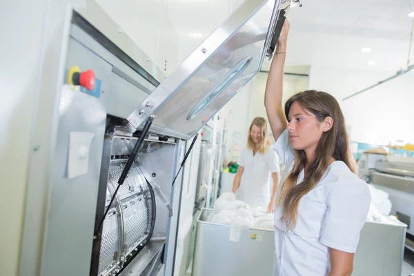 Senhora levantando porta aberta da máquina na lavanderia profissional — Fotografia de Stock