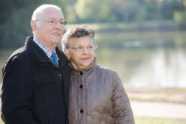 Casal idoso ao lado de um lago — Fotografia de Stock