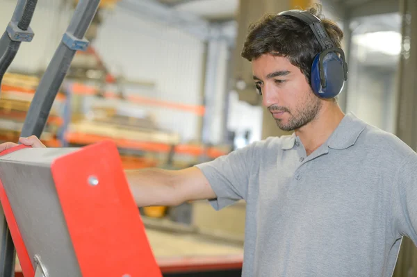 Man in fabriek oor verdedigers dragen — Stockfoto