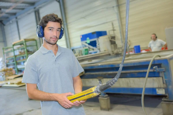 Workman bär hörselskydd, håller handkontrollen — Stockfoto