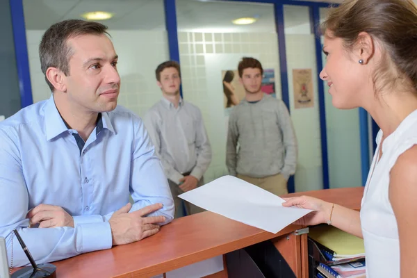 Lady entregando el formulario al hombre en recepción — Foto de Stock