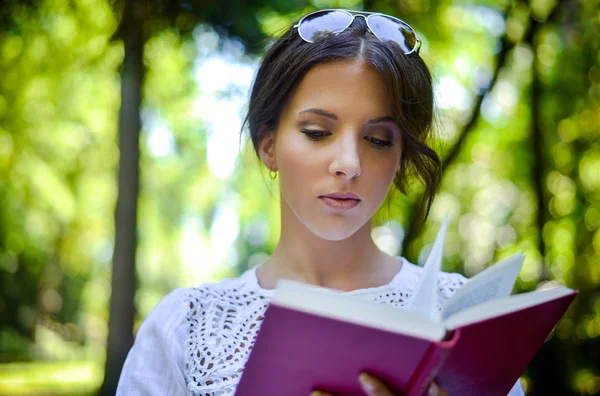 Kvinnan läsa boken utomhus i fridfulla skogen — Stockfoto