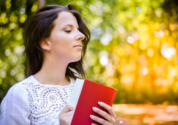 Parkta bir kitap tutan düşünceli kadın