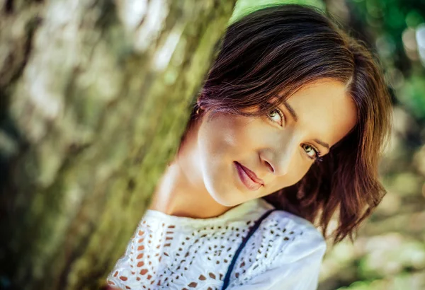 Güzel kadın bir ağacın arkasından bakmak