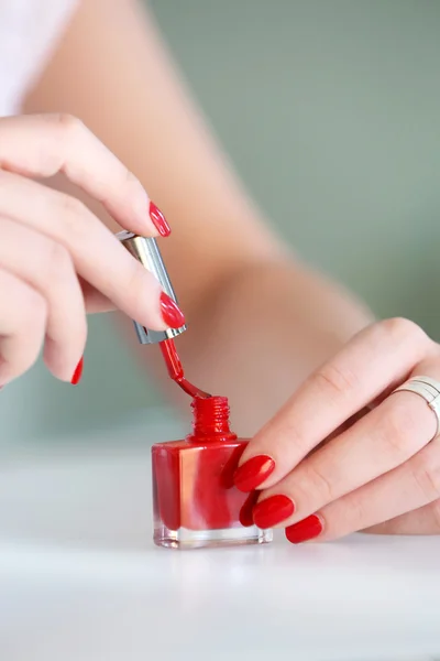 Wanita mengoleskan cat kuku merah di jarinya — Stok Foto