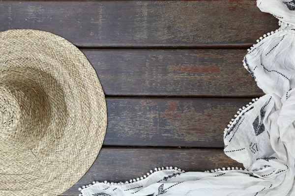 Chapéu de palha e um cachecol no fundo de madeira — Fotografia de Stock