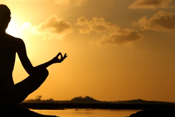 Silhouette of woman practicing yoga during sunset at the seaside — Stock Photo, Image