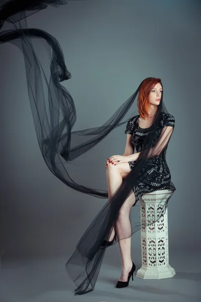 Red hair woman posing in the studio with big black muslin fabric — Stock Photo, Image