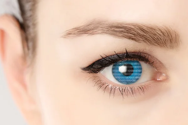 Primer plano del ojo azul de la mujer mostrando códigos binarios — Foto de Stock