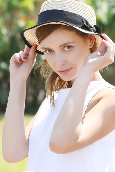 Ritratto esterno di ragazza in abito bianco con cappello di paglia in mano — Foto Stock
