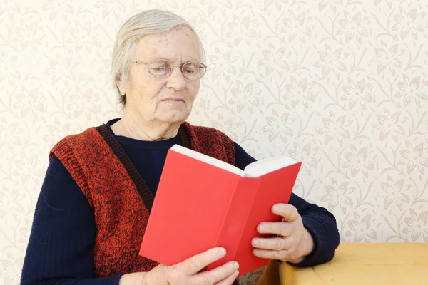 Abuela sentada en casa y leyendo un libro — Foto de Stock