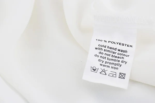 Fabric composition and washing instructions label on white shirt — Stock Photo, Image