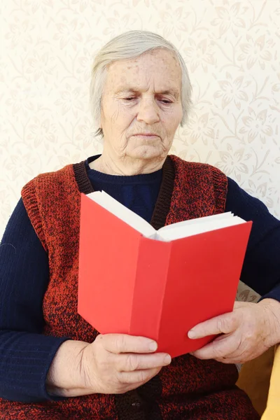 Grand-mère assise à la maison et lisant un livre — Photo