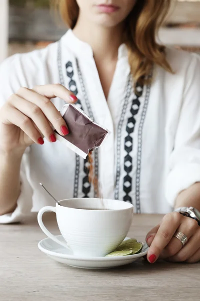 Hora do chá. Menina no café adicionando açúcar na xícara de chá — Fotografia de Stock