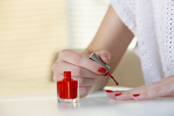 여자-그녀의 손가락에 빨간 매니큐어를 적용 브러시에 초점. — 스톡 사진
