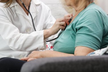 Tıp çalışanı, yaşlı bir hastanın nabzını ölçmek için steteskop kullanıyor. Sağlık kontrolü..