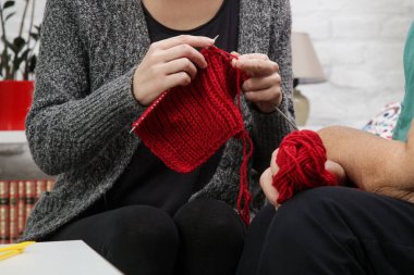 Grandomther ve torunu aile bağlarını güçlendirirken yaratıcı ve eğlenceli yollarla birlikte zaman geçiriyorlar. Kıdemli bir kadın, genç bir kadına örgü örmeyi öğretiyor. Yapı ve DIY kavramı.