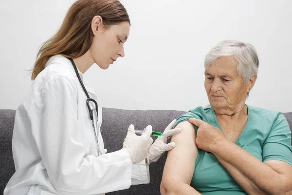 Senior woman receiving vaccine. Medical worker vaccinating an elderly patient against flu, influenza, pneumonia or coronavirus.