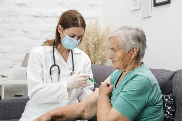 Senior woman receiving vaccine. Medical worker vaccinating an elderly patient against flu, influenza, pneumonia or coronavirus.