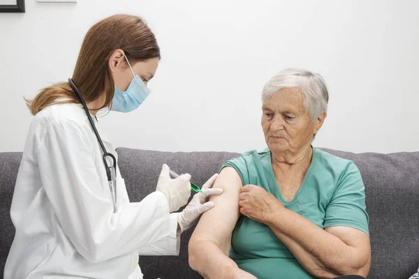 Senior woman receiving vaccine. Medical worker vaccinating an elderly patient against flu, influenza, pneumonia or coronavirus.