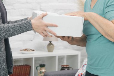 Yaşlı kadın müşteri paket kutusunu evde alıyor..