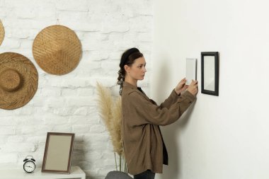 Yeni evin duvarlarında resim çerçeveleri düzenleyen kadın, ev geliştirme konseptini bozuyor.