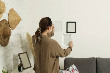 Yeni evin duvarlarında resim çerçeveleri düzenleyen kadın, ev geliştirme konseptini bozuyor.