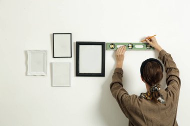 Yeni evin duvarlarında resim çerçeveleri düzenleyen kadın, ev geliştirme konseptini bozuyor.