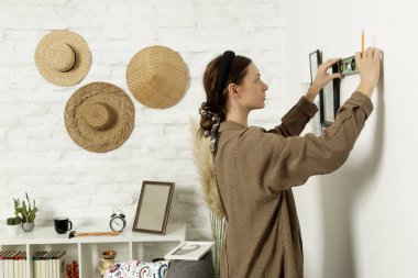 Yeni evin duvarlarında resim çerçeveleri düzenleyen kadın, ev geliştirme konseptini bozuyor.