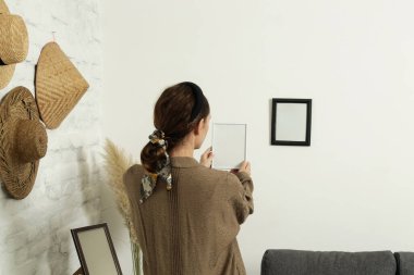 Yeni evin duvarlarında resim çerçeveleri düzenleyen kadın, ev geliştirme konseptini bozuyor.