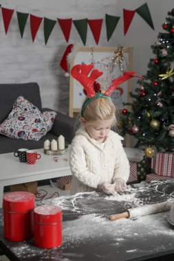 Sevimli küçük kız mutfakta unla oynuyor, Noel kurabiyesi hazırlıyor. Aile tatilinin neşesi evde.
