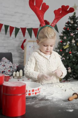 Sevimli küçük kız mutfakta unla oynuyor, Noel kurabiyesi hazırlıyor. Aile tatilinin neşesi evde.