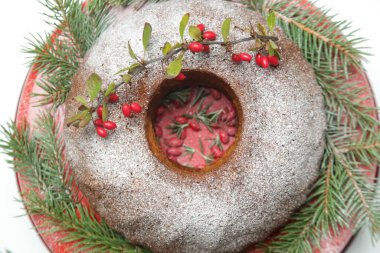 Kırmızı böğürtlenler ve beyaz arka planda köknar dallarıyla süslenmiş şenlikli kek..